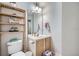 Bathroom showcasing a toilet, sink, wooden shelf, and a mirror, plus textured walls at 2804 Polvadero Ln # 107, Orlando, FL 32835