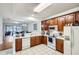 Open concept kitchen features wood cabinets, white appliances, tile flooring, and a view into the living area at 2804 Polvadero Ln # 107, Orlando, FL 32835