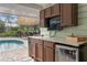Outdoor kitchen features brown cabinetry and a mini fridge at 2931 Sunbittern Ct, Windermere, FL 34786