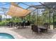 Screened in poolside dining area featuring a shade canopy with a view of the lush backyard and tropical landscaping at 2931 Sunbittern Ct, Windermere, FL 34786