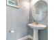 Stylish powder room featuring pedestal sink, round mirror, and soft blue paint at 3127 Via Otero Dr, Kissimmee, FL 34744