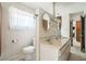 Bathroom featuring a dual sink vanity, decorative mirrors and lighting, and separate toilet area at 450 Cassady St, Umatilla, FL 32784