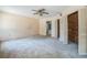 Spacious bedroom featuring neutral carpet, ceiling fan, and access to an en-suite bathroom and large closet at 450 Cassady St, Umatilla, FL 32784