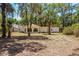 Exterior view of a white home featuring a distinctive round sunroom and a natural landscape with mature trees at 450 Cassady St, Umatilla, FL 32784