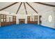 Spacious living room with vaulted ceilings, exposed beams, blue carpet, and fireplace at 450 Cassady St, Umatilla, FL 32784
