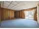Cozy living room with wood paneled walls, sliding glass door to the backyard, and carpeted flooring at 450 Cassady St, Umatilla, FL 32784