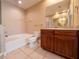 Bright bathroom with a soaking tub, vanity with wood cabinets, and tile flooring at 4504 Messina Dr, Lake Mary, FL 32746