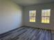 Bright bedroom with two windows, gray wood flooring, and neutral paint creating a peaceful atmosphere at 489 Marion Oaks Golf Rd, Ocala, FL 34473