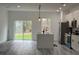 Open-concept kitchen with stainless steel appliances, center island, and sliding glass door to the backyard at 489 Marion Oaks Golf Rd, Ocala, FL 34473