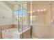 This bathroom features tile floors, a glass shower enclosure, and a large bathtub with a window at 5029 Southlawn Ave, Orlando, FL 32811