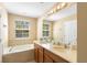 Primary bathroom boasts double sinks, vanity, soaking tub, tile and large mirror at 5373 Via Appia Way, Sanford, FL 32771