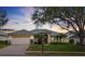 Charming one-story home with a well-manicured lawn, mature trees, and a brick-paved driveway leading to a two-car garage at 548 Burford Cir, Davenport, FL 33896