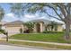 Charming one-story home with a well-manicured lawn, mature trees, and a brick-paved driveway leading to a two-car garage at 548 Burford Cir, Davenport, FL 33896