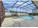 Backyard pool and hot tub enclosed by a screen, surrounded by lush greenery and a white fence at 548 Burford Cir, Davenport, FL 33896