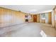 Open living room featuring paneled walls, a view into the kitchen, and bright natural light from the windows at 5900 Lyle St, Orlando, FL 32807