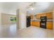 Eat-in kitchen with wooden cabinets, black appliances, and tile flooring at 913 Jacaranda Dr, Lady Lake, FL 32159