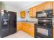 Well-lit kitchen featuring classic wood cabinetry and modern black appliances at 913 Jacaranda Dr, Lady Lake, FL 32159