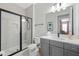 Modern bathroom with a glass-enclosed shower, gray vanity, and white countertops at 942 Jack Nicklaus Ct, Kissimmee, FL 34747
