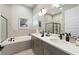 Modern bathroom featuring a double vanity, bathtub, and glass-enclosed shower at 942 Jack Nicklaus Ct, Kissimmee, FL 34747