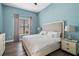 Blue bedroom featuring a white bed with decorative pillows, bedside tables, and wooden floors at 942 Jack Nicklaus Ct, Kissimmee, FL 34747