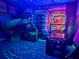 The neon-lit game room has nostalgic design, multiple arcade games, and unique lighting at 942 Jack Nicklaus Ct, Kissimmee, FL 34747