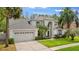 Exterior view of a two-story home with well-kept landscaping, lush palm trees, and a three car garage at 13325 Falcon Pointe Dr, Orlando, FL 32837