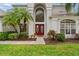 Charming front entrance with a red double door, lush landscaping, and a well-manicured lawn at 13325 Falcon Pointe Dr, Orlando, FL 32837