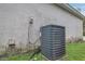 Close-up of an updated central air conditioning unit outside of home with grassy lawn and stucco wall at 1525 Rivers Edge Dr, Orlando, FL 32825