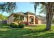 Well-maintained single-story home with a lush green lawn, complemented by a palm tree and colorful flower beds at 1924 Eloise Cove Dr, Winter Haven, FL 33884