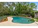 In-ground pool surrounded by a concrete deck, metal fence, and lush landscaping at 3553 Jericho Dr, Casselberry, FL 32707