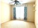 Bedroom featuring neutral walls and carpet, a ceiling fan, and a large window with patterned curtains at 3810 Blue Dasher Dr, Kissimmee, FL 34744