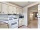 Compact kitchen featuring white appliances and upper cabinets with an adjacent room at 412 N Boyd St, Winter Garden, FL 34787