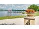 Scenic view of the lake with a pier and gazebo, surrounded by lush greenery and vibrant flower pots at 4457 Anson Ln, Orlando, FL 32814