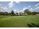 Expansive green lawn with walking path, mature landscaping, and a charming clubhouse in the background at 4457 Anson Ln, Orlando, FL 32814