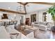 Open-concept living room with hardwood floors, wood beam ceilings, and a elegant chandelier at 4457 Anson Ln, Orlando, FL 32814