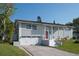 Charming home exterior featuring an attached garage, solar panels, manicured lawn, and a red front door at 504 Teakwood Dr, Altamonte Springs, FL 32714