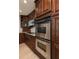 Close-up of a kitchen area with dark wood cabinets, stainless steel double oven, granite counters and wood look floors at 504 Teakwood Dr, Altamonte Springs, FL 32714