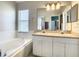 Bathroom featuring a soaking tub, shower, dual vanity sinks, and neutral-toned tile at 527 Durango Loop St, Davenport, FL 33897