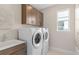 Bright laundry room features a sink, Whirlpool washer and dryer, cabinets, and a window for natural light at 6799 Willow View Ave, Orlando, FL 32829