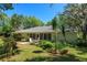 Sliding glass doors look out from the home to a backyard with mature tropical landscaping and lawn furniture on a patio at 2930 Westgate Dr, Eustis, FL 32726