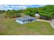 Aerial view of a light blue home on a large, green lawn surrounded by lush trees and blue skies at 10544 Parkway Dr, Clermont, FL 34711