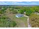 Scenic aerial view of a light blue home near a lake and surrounded by lush green trees and vegetation at 10544 Parkway Dr, Clermont, FL 34711