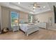 Bright main bedroom featuring a ceiling fan, light walls, tray ceiling, hardwood floors, and large windows at 10544 Parkway Dr, Clermont, FL 34711