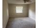 Empty bedroom with carpet flooring, featuring a ceiling fan, window, and neutral walls at 1060 Walt Williams Rd, Lakeland, FL 33809