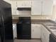 Kitchen with updated gray wood flooring featuring white cabinets, black appliances, and dual sink at 1060 Walt Williams Rd, Lakeland, FL 33809