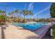 Community pool with stainless steel railings surrounded by palm trees, and several lounge chairs under blue umbrellas at 1290 Grady Ln # 20232, Davenport, FL 33896