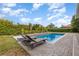 Beautiful pool area with lush, mature landscaping and lounge chairs creating a private oasis at 1403 Lake Whitney Dr, Windermere, FL 34786