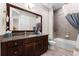 Bathroom featuring a dark wood vanity, large mirror, shower and tub combination, neutral paint, and tile flooring at 14090 Alafaya Oak Bnd, Orlando, FL 32828