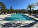 Clear view of a large community pool with lounge chairs, palm trees, and lush greenery in the background at 14090 Alafaya Oak Bnd, Orlando, FL 32828