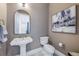 Powder room featuring a pedestal sink, modern fixtures, and decorative artwork at 16728 Bolsena Dr, Bella Collina, FL 34756